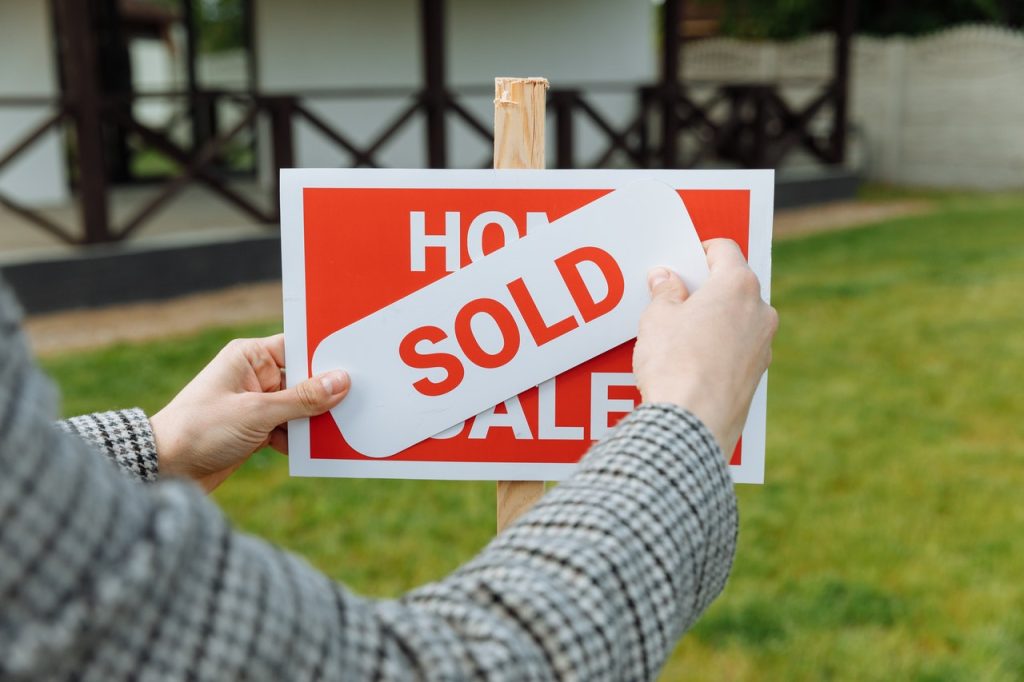 A Man Holding a Placard With Text Sold With Thumb 