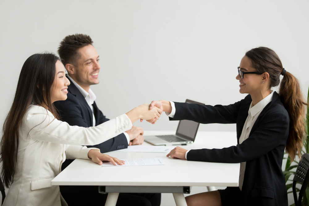 Smiling Diverse Businesswomen Shake Hands at Group Meeting