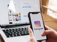 A Woman Holds an Smartphone With Instagram Application on the Screen at Cafe