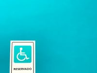 a sign that is on a pole in front of a blue wall disabled person, wheelchair, paper documents