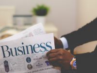 person wearing suit reading business newspaper cloud computing, scalability, business growth