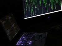 A laptop computer sitting on top of a desk hacker, cybersecurity, data breach