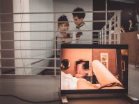 a picture of a man and a woman in a room people watching video, subtitles, closed captions