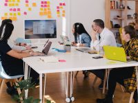 five person by table watching turned on white iMac team choosing software, invoicing app comparison, office discussion