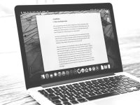 Laptop displays a document, possibly a letter. writing report interface, grammar check tool, plagiarism detection