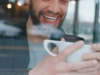 How to Pay Off Debt Fast: 5 Smart Strategies smiling man holding white ceramic mug happy person watching video converted device screen smile