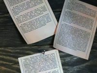 three pieces of paper on top of a wooden table proof copy, printed book, working at desk