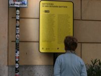 a woman standing next to a yellow sign guerrilla marketing, street advertising, public installations
