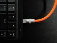 A close up of a computer keyboard with an orange cord HDMI cable connected to graphics card, DisplayPort cable close up, GPU ports on PC, monitor cable swap