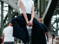A woman is sitting on top of a pole urban fashion, modern streetwear, minimal style