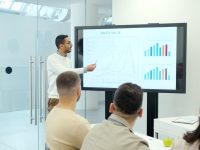 6 WaitlistPro Competitor Tools for Pre‑Order and Waitlist Monetization Man presenting charts on a large screen to audience. ai ecommerce automation dashboard analytics graphs digital marketing