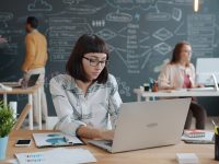 Woman working on laptop in modern office with team. laptop screen seo dashboard shared workspace people working