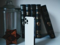 2 of spade playing card smartphone with apple books app, audiobook library screen, headphones on desk