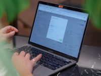 a woman sitting at a table using a laptop computer search intent example, search results page, user typing on laptop