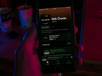 black samsung android smartphone on persons hand iphone music settings screen, sync library toggle, apple music app interface