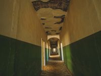 Long, empty hallway with deteriorating walls. genshin underground seelie floating ancient corridor