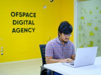 Tools Startups Explore Instead of ClickUp Goals for OKRs and Project Management man in blue and white checkered dress shirt sitting on black chair startup team planning session office whiteboard laptops