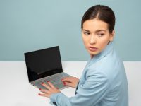 woman using laptop and looking side person frustrated at laptop, website blocked screen, troubleshooting concept