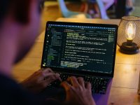 A person sitting at a table with a laptop person using laptop seo optimization, structured data code screen, digital marketing workspace