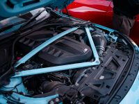 Light blue car engine with hood open mechanic using tablet, car engine bay, OBD scanner connected